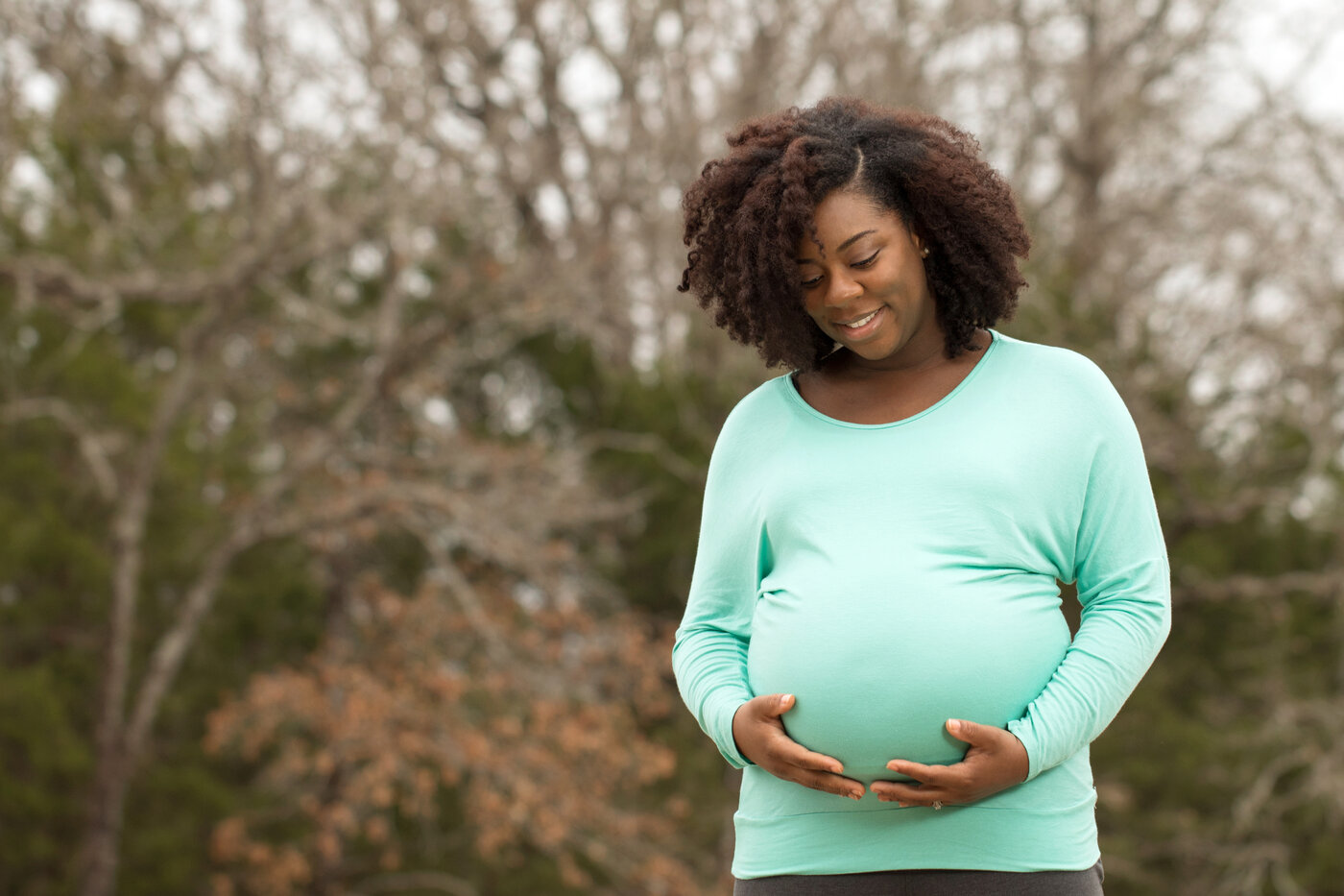 Pregnant woman outside with trees behind